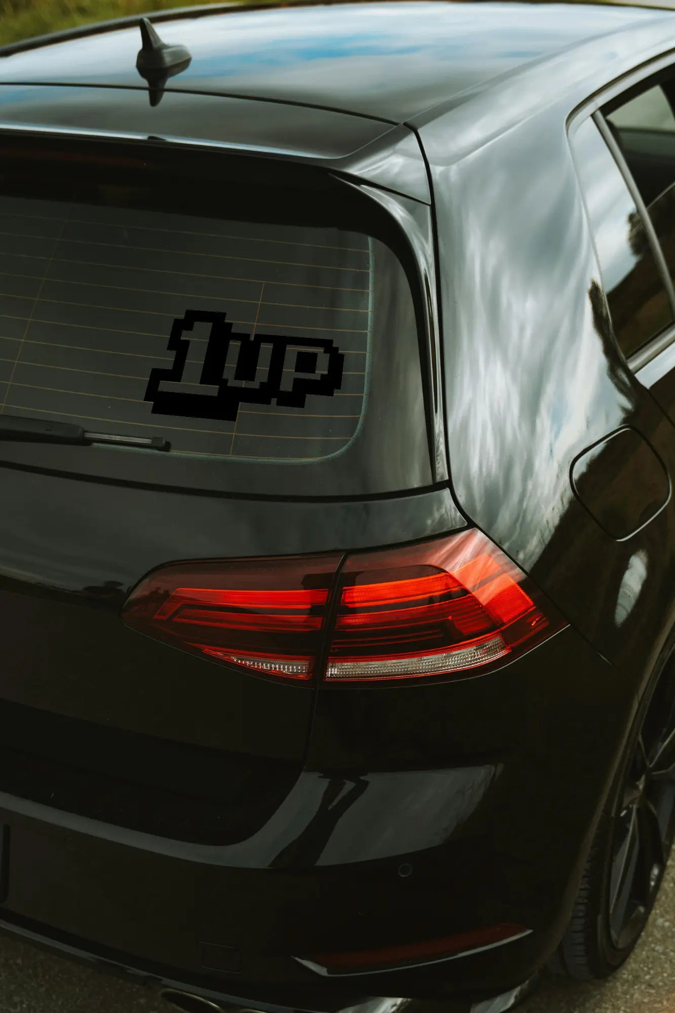 1up matrica fekete színben az autó hátsó ablakán.