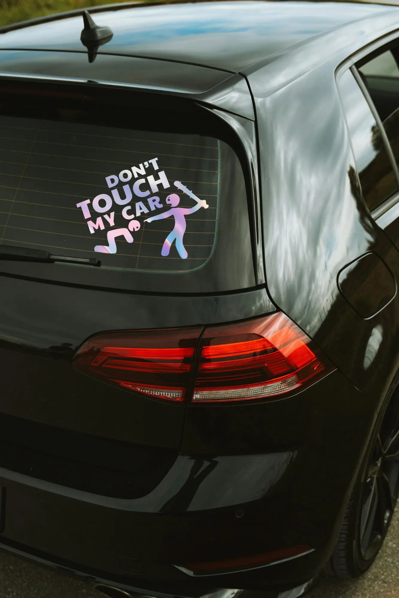 Don't Touch My Car matrica hologram színben az autó hátsó ablakán.