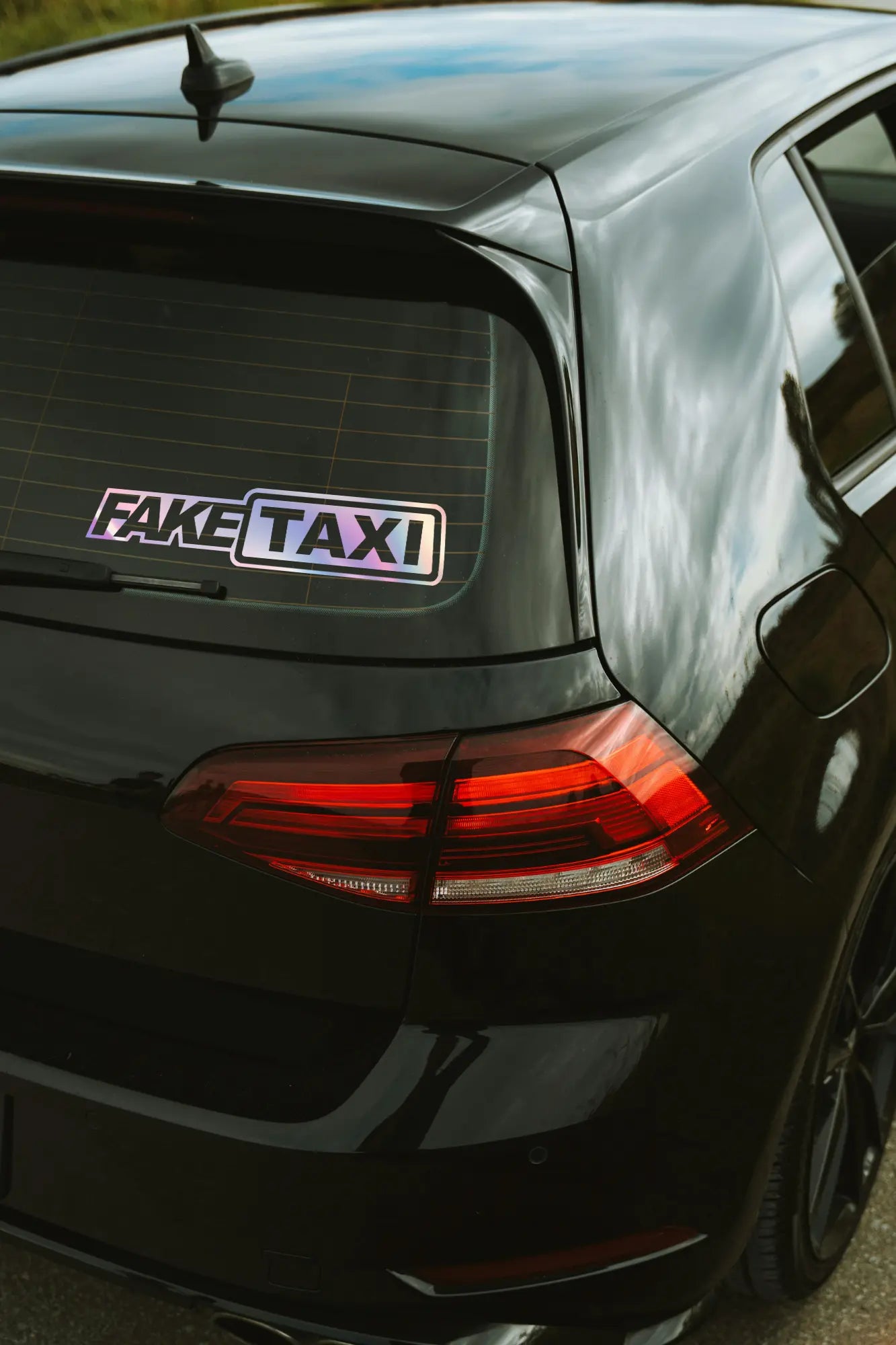 Fake Taxi matrica hologram színben az autó hátsó ablakán.