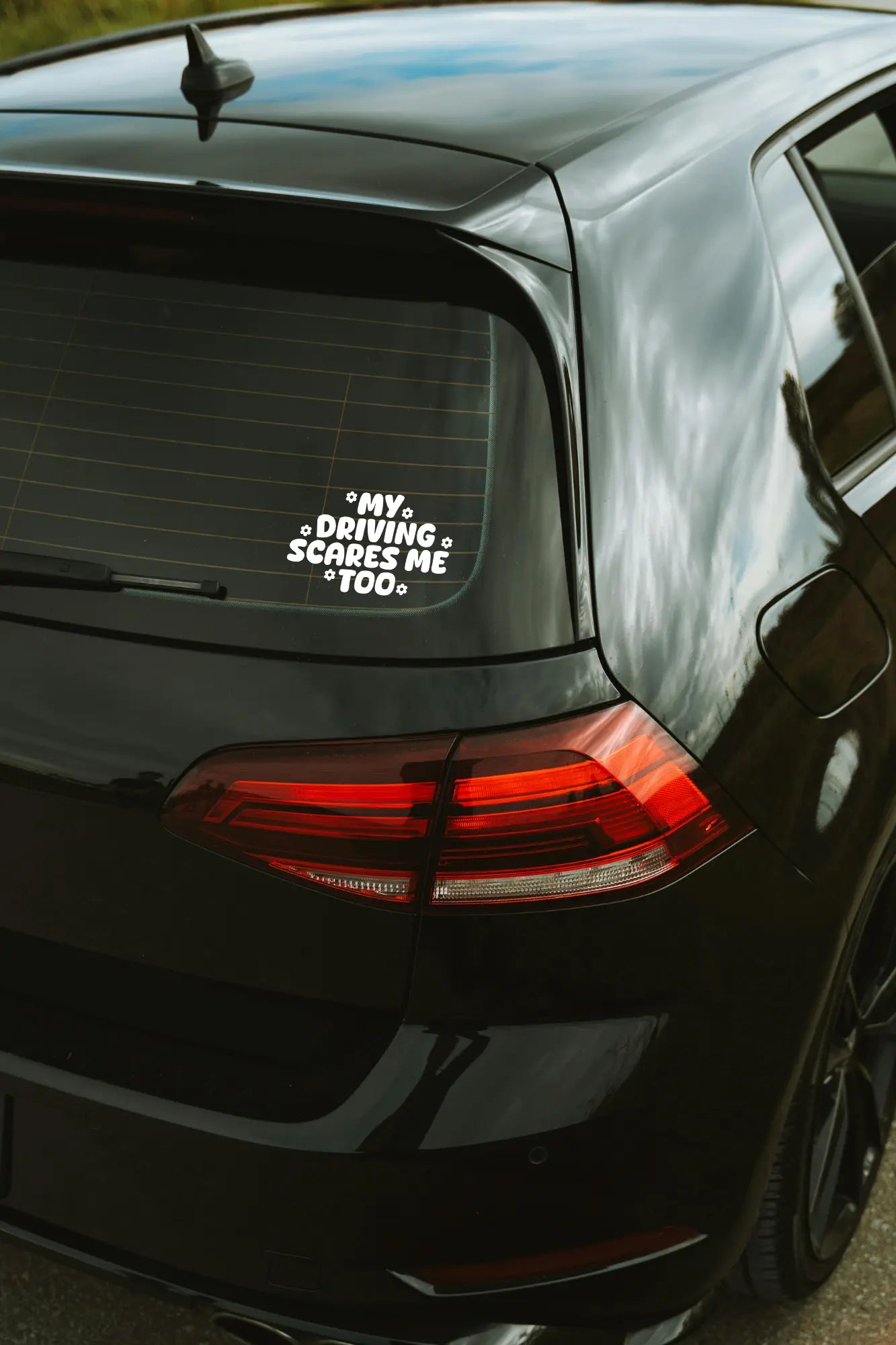 My Driving Scares Me Too matrica fehér színben az autó hátsó ablakán.